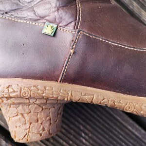 Detailed view of the cork-textured heel and dark brown leather craftsmanship, featuring the El Naturalista eco frog logo.