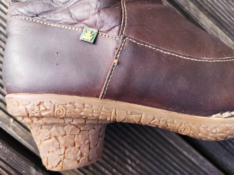 Detailed view of the cork-textured heel and dark brown leather craftsmanship, featuring the El Naturalista eco frog logo.