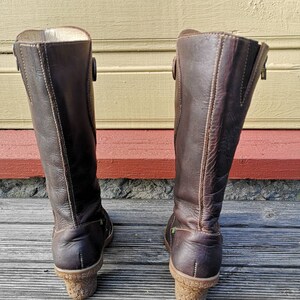 Back view of El Naturalista boots, showing their sturdy cork-textured heels, minimalist stitching, and sustainable leather craftsmanship.