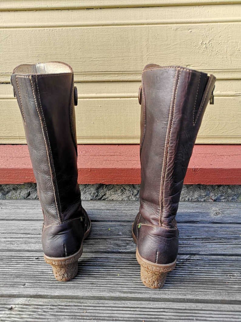Back view of El Naturalista boots, showing their sturdy cork-textured heels, minimalist stitching, and sustainable leather craftsmanship.