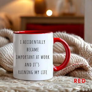 May include: White ceramic mug with a red interior and handle. The mug features the text "I ACCIDENTALLY BECAME IMPORTANT AT WORK AND IT'S RUINING MY LIFE" in black. The word "RED" is also visible in the image.