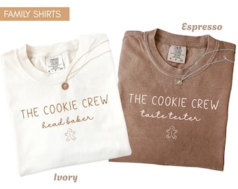 May include: Two short-sleeve crew neck t-shirts. The ivory shirt features brown text reading THE COOKIE CREW and head baker with a gingerbread man icon. The espresso shirt features white text reading THE COOKIE CREW and taste tester with a gingerbread man icon.