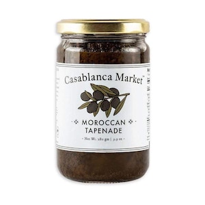 Pode incluir: Um frasco de vidro de tapenade marroquina com um rótulo branco que diz "Casablanca Market" e "Tapenade marroquina". O rótulo também inclui um desenho de azeitonas em um galho. O frasco contém 280 gramas de tapenade.
