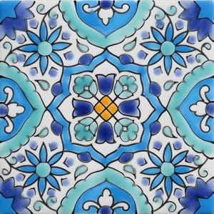 Może przedstawiać: Kwadratowa płytka ceramiczna z powtarzającym się wzorem kwiatowym w odcieniach niebieskiego, turkusowego i białego. Wzór przedstawia stylizowane kwiaty, liście i kształty geometryczne, z centralnym żółtym akcentem. Czarne kontury definiują wzory.