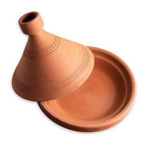 Puede incluir: Una tagine de terracota con una tapa abovedada. La tapa tiene un patrón decorativo de líneas. La tagine es una olla de cocción tradicional marroquí.