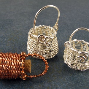 May include: Three miniature wire baskets, one copper and two silver, with a woven design. The baskets are all approximately 5 cm tall.