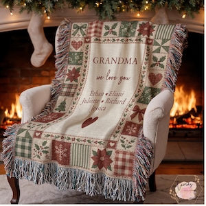 May include: A woven throw blanket featuring a cream-colored center with the text GRANDMA we love you, followed by the names Ethan, Eliani, Juliette, Richard, and Jessica. The border displays a patchwork pattern of poinsettias, hearts, and snowflakes.