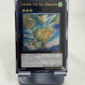 May include: A blue and gold "Leviair the Sea Dragon" trading card from the Yu-Gi-Oh! Trading Card Game. The card is a "Aqua/XYZ/Effect" monster with an attack power of 1800 and a defense power of 1600. The card text reads: "2 Level 3 monsters. Once per turn: You can detach 1 Xyz Material from this card to target 1 banished Level 4 or lower monster, Special Summon that target to your side of the field."