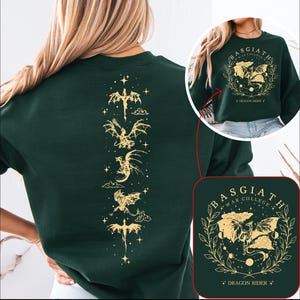 May include: Green sweatshirt with a gold dragon design on the back. The front of the sweatshirt has a gold dragon design with the text "Basgiath War College Dragon Rider".