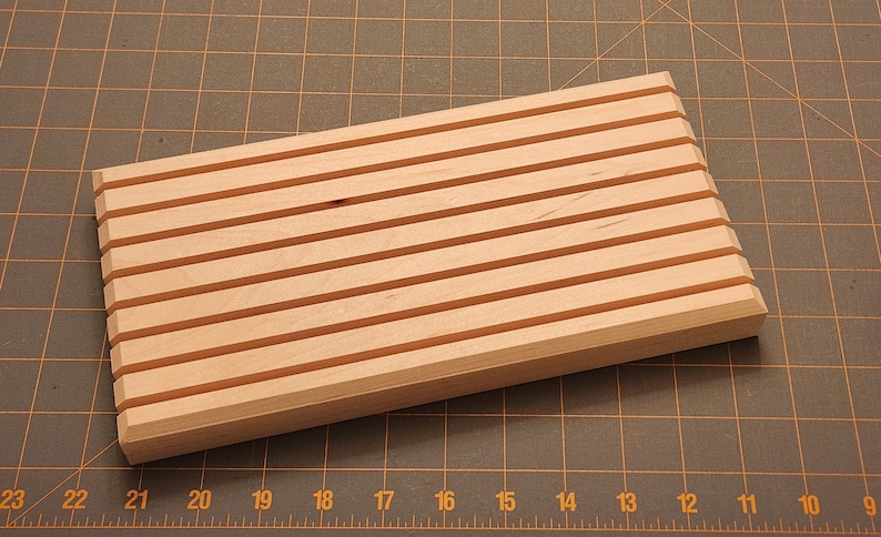 Puede incluir: Una bandeja de madera con ocho ranuras paralelas, ideal para organizar y exhibir objetos peque&ntilde;os.