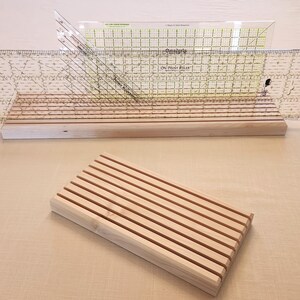 Puede incluir: Un estante de madera para reglas con dos reglas de pl&aacute;stico transparente. Las reglas est&aacute;n marcadas en pulgadas y tienen el texto "On Point Ruler" impreso. El estante est&aacute; hecho de madera natural y tiene un dise&ntilde;o de listones.