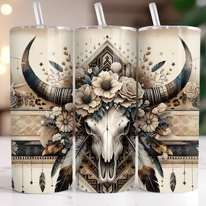 May include: A white tumbler with a brown and white skull with floral accents and a geometric pattern. The skull is surrounded by feathers and a brown and white bull horn.