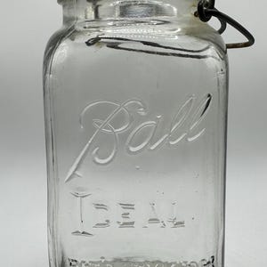 May include: A clear glass Ball brand jar with a wire bail closure. The jar has the text "IDEAL" and "PAT'D JULY 4, 1903" embossed on the bottom.