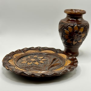 May include: A set of two brown ceramic dishes with intricate floral carvings. The larger dish is a plate with a scalloped edge, and the smaller dish is a vase.