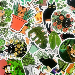 May include: A collection of colourful stickers featuring cats, plants and flowers. The stickers have a whimsical and playful style. Some stickers feature the text "Plant + Cat Lover".
