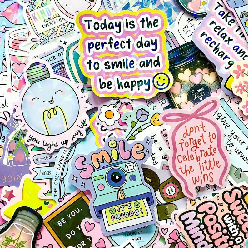 May include: A collection of colorful stickers with various designs and text. The stickers feature phrases like "Today is the perfect day to smile and be happy" and "It's Friday!" Other designs include a camera, lightbulb, and floral elements.