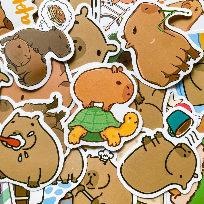 May include: A collection of cartoon capybara stickers in various poses. Some stickers show capybaras with food, on a turtle, or with grass in their mouths. The stickers are brown, orange, green, and white.
