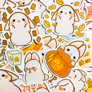 May include: A set of colorful stickers featuring cartoon bunnies holding red envelopes and gold coins. The stickers have a Chinese New Year theme and feature the Chinese character for "fortune".