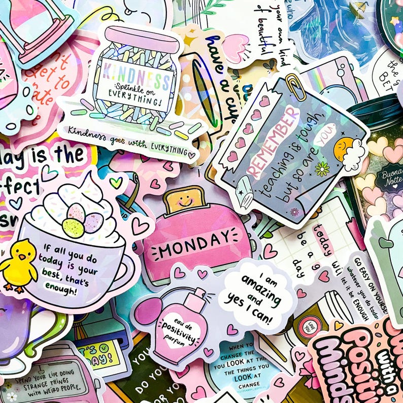 May include: A collection of colorful stickers with positive affirmations and cute illustrations. Designs include a jar of sprinkles, a toaster with "MONDAY", a perfume bottle, and a coffee cup. Text includes "Kindness", "Remember", and "I am amazing".