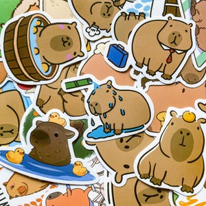 May include: A collection of various capybara stickers in different poses and settings. Some stickers show capybaras in a barrel, with rubber duckies, and wearing a tie. The stickers are brown and white with black outlines.