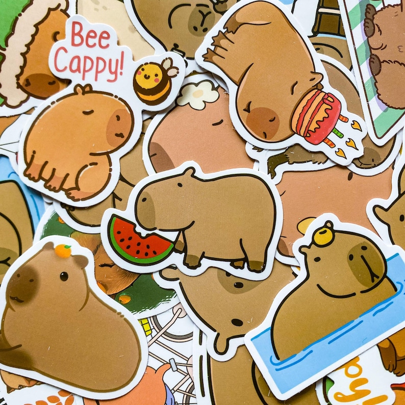May include: A collection of cartoon stickers featuring capybaras in various poses. Some capybaras are eating watermelon, wearing party hats, or floating in water. One sticker has the text "Bee Cappy!" with a bee.