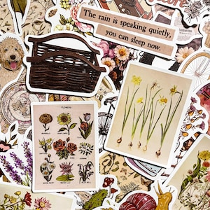 May include: A collection of vintage-style stickers featuring floral designs, a wicker basket, a quote about rain, and a botanical illustration of daffodils. The stickers are printed on white paper with a distressed look.