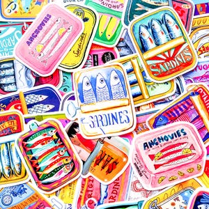 Può includere: Una collezione di adesivi colorati con illustrazioni di sardine e acciughe in vari design di scatole. Gli adesivi presentano diverse combinazioni di colori, tra cui rosa, giallo e blu, con testi come "Sardines" e "Anchovies".