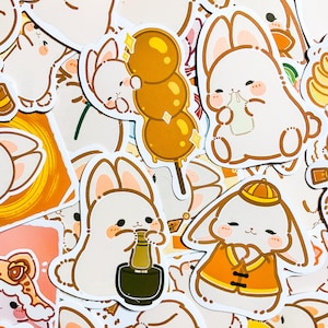 May include: A collection of colorful stickers featuring cute cartoon bunnies in various poses. The stickers are on a white background and include a bunny holding a bottle, a bunny wearing a traditional Chinese hat, and a bunny holding a skewer of mochi.