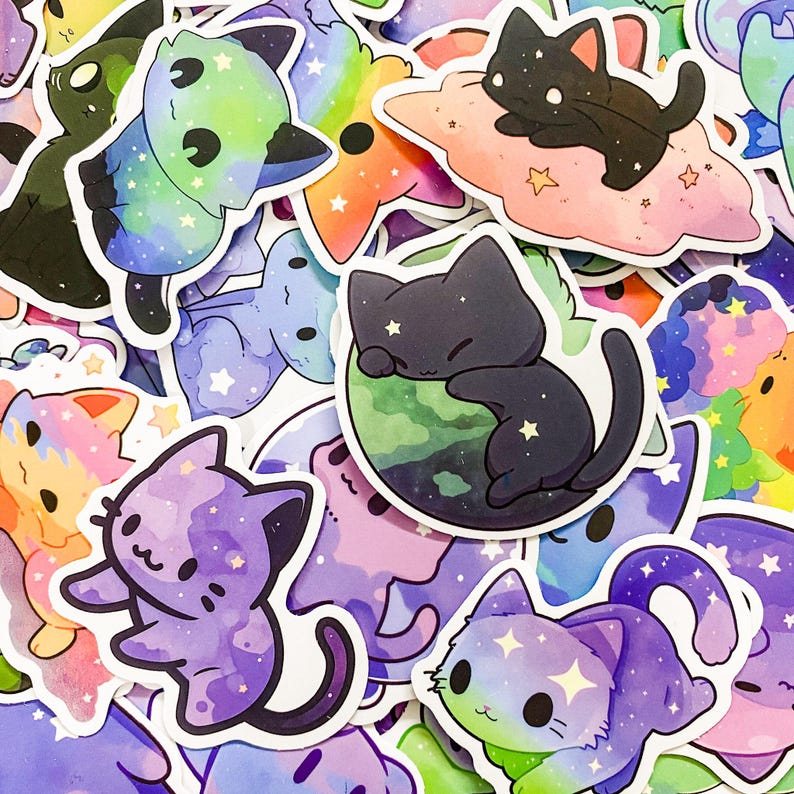 May include: A collection of colorful cat stickers with galaxy and star designs. The stickers feature various poses and expressions, including a cat sleeping on a planet, a cat on a cloud, and a cat with a rainbow tail.