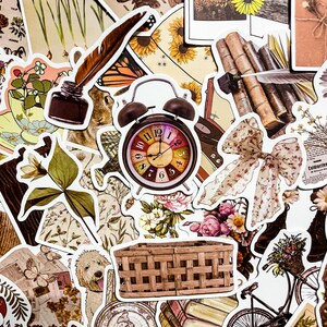 May include: A collection of vintage-style stickers featuring various designs, including a clock, a wicker basket, a floral bouquet, a butterfly, a quill pen, a book stack, a bow, and a bicycle. The stickers are printed on white paper with a glossy finish.