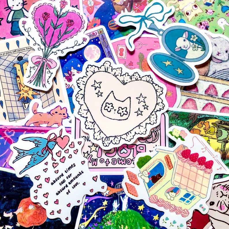 Pu&ograve; includere: Una collezione di adesivi colorati con vari disegni. Include un adesivo a forma di cuore con una faccia di gatto e stelle, un uccello blu che trasporta cuori e una casa con fragole in cima. Il testo "absurd times call for absurd amounts of love" &egrave; visibile.
