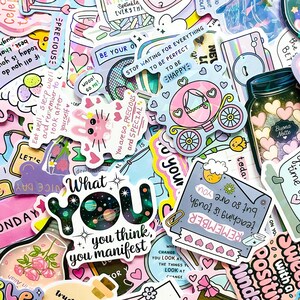 May include: A collection of colorful stickers with various designs and text. Stickers include a pink carriage, a jar with hearts, a bunny, and text that says "What you think, you manifest."