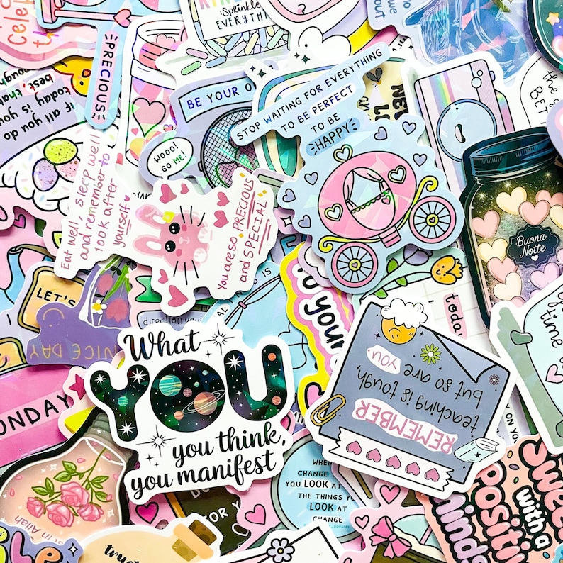 May include: A collection of colorful stickers with various designs and text. Stickers include a pink carriage, a jar with hearts, a bunny, and text that says "What you think, you manifest."