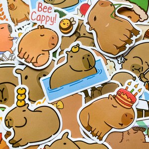 May include: A collection of cartoon capybara stickers in various poses. Some stickers feature the text "Bee Cappy!" and a smiling bee. Other stickers show capybaras with a birthday cake, in water, and with other accessories.