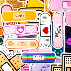 May include: A selection of colourful bandage stickers with diverse designs and text. Some bandages feature hearts, pixelated patterns, and the phrases "I'm fine" and "Everything will be Okay." Other designs include a rainbow and peach illustrations.