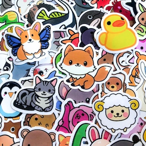 Könnte beinhalten: Eine Sammlung bunter Aufkleber mit verschiedenen Zeichentieren. Die Aufkleber zeigen einen Corgi mit Schmetterlingsflügeln, einen Fuchs, eine Katze, eine Ente, ein Schaf und einen Pinguin. Die Aufkleber sind in verschiedenen Größen und Formen.