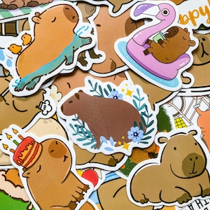 May include: A collection of colorful capybara stickers. Some stickers feature capybaras with birthday cakes, swimming, or relaxing on a flamingo float. Other stickers show capybaras surrounded by flowers or simply sitting.