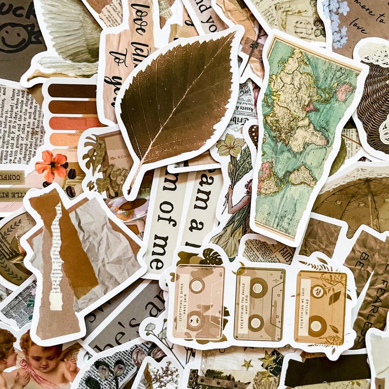 May include: A collection of vintage-style stickers featuring various designs, including a leaf, a world map, a cassette tape, and text phrases like "love like", "am a", and "dream of me". The stickers are printed on a white background with brown and beige accents.