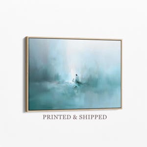 Pode incluir: Impressão de arte abstrata em uma moldura de madeira. A obra apresenta uma paisagem serena e borrada em tons de verde-azulado e branco, com uma figura no centro. O texto "PRINTED & SHIPPED" está na parte inferior.