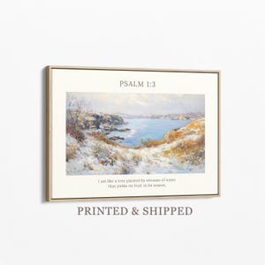 May include: Framed art print featuring a landscape painting of a coastal scene with snow-covered land and a body of water. The text "PSALM 1:3" is at the top, with a quote below. The frame is a light brown color.