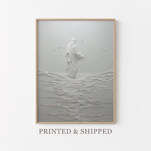 Puede incluir: Una impresión artística enmarcada en escala de grises representa una figura con túnicas flotantes de pie en el agua, con pájaros en el cielo. La obra de arte tiene una apariencia texturizada en bajorrelieve. El marco es de color madera clara. El texto "PRINTED & SHIPPED" está en la parte inferior.
