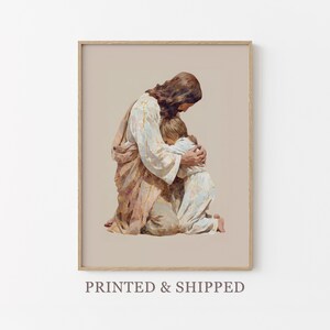 Peut inclure: Impression d'art encadrée représentant une figure en robes embrassant un enfant. Les couleurs douces, beige, marron et blanc, créent une atmosphère chaleureuse. Le texte "PRINTED & SHIPPED" est visible en bas de l'image.