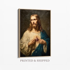 以下が含まれることがあります： 長い髪とひげを生やし、白と青のローブを着た男性の額装された肖像画。男性は炎の心臓を持っています。「PRINTED & SHIPPED」というテキストがフレームの下部にあります。