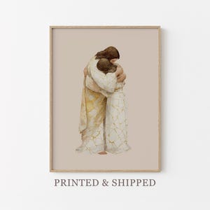 Puede incluir: Impresión artística enmarcada con una ilustración en acuarela de dos figuras abrazándose. Las figuras visten túnicas fluidas blancas y doradas, sobre un fondo neutro. El texto "PRINTED & SHIPPED" está en la parte inferior.