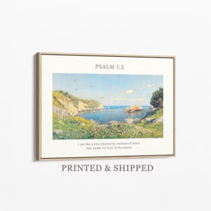 May include: A framed print featuring a coastal landscape painting with a serene bay, cliffs, and blue sky. The text "PSALM 1:3" is at the top, with a quote below. The frame is a light brown color.