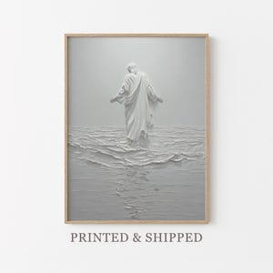 Puede incluir: Una impresión enmarcada que presenta una figura blanca con túnicas fluidas de pie en el agua. La obra de arte tiene una apariencia texturizada, casi esculpida, con una paleta de colores apagados de blancos y grises. La imagen evoca una sensación de serenidad y espiritualidad.