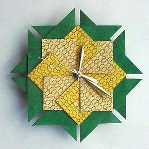 May include: A green and yellow origami clock with a silver face and hands.