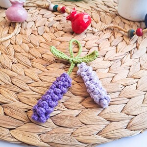 Lavender keychain crochet pattern shown on woven mat with decorative background – cozy handmade gift idea.