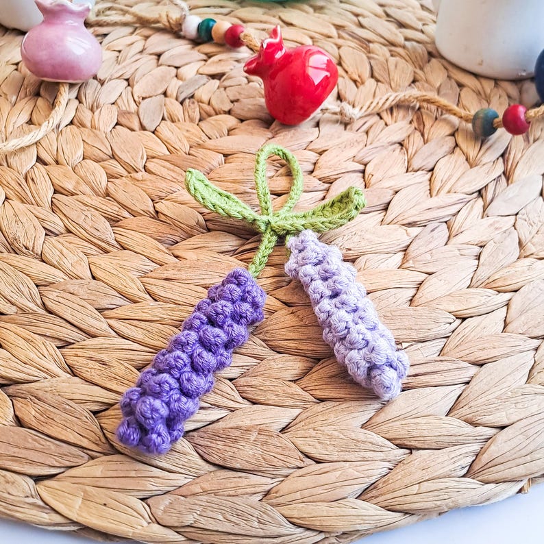 Lavender keychain crochet pattern shown on woven mat with decorative background – cozy handmade gift idea.