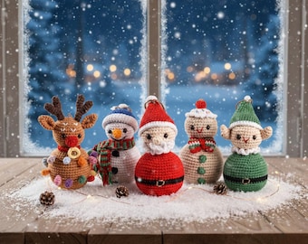 May include: A collection of five handmade crochet Christmas ornaments. The ornaments include a reindeer, snowman, Santa Claus, a second snowman, and an elf. The ornaments are set on a snowy surface with a wintery background.